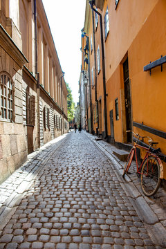 Two Women Walk down the Cobblestone Path of a Narrow Alley with a Bicycle Rested against a Building in the Gamla Stan Neighborhood of Stockholm, Sweden