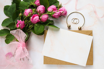 postcard mockup. a small bouquet of pink roses, a wedding ring and an envelope. space for text. wedding invitation. flat lay