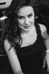 Young beautiful biker woman in a black tank top and leather pants sits on a motorcycle from behind. The concept of speed and freedom. Soft selective focus. Black and white photo.