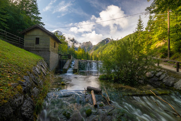 Fototapeta na wymiar small waterfall on a stream flowing out of Lake Laghi di Fusine in the Julian Alps in Italy