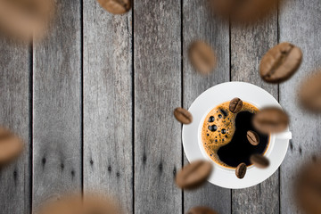 Top view of brown roasted coffee beans falling and flying to coffee cup.Represent breakfast for energy and freshness concept.