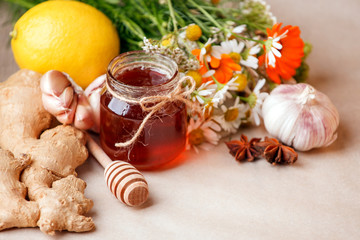Harvesting herbs, flower garlic, lemon, ginger root, honey in jar - concept of seasonal winter autumn fall days, beverage for cold flu treament, alternative meidicne