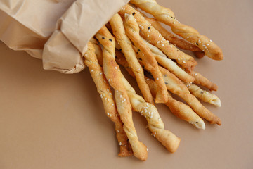 Crispy snack in a paper bag. Salty sesame bread sticks for a quick bite