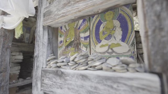 An ancient wooden Buddhist prayer hut. The camera zooms forward showing old paintings of the Buddha.
