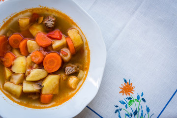 Traditional homemade Hungarian hot goulash soup with mear, potato, carrot and mushrooms in a white...