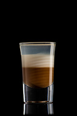B52 coffee creamy alcohol cocktail in three layers in a shot glass on a black background