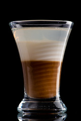 B52 coffee creamy alcohol cocktail in three layers in a shot glass on a black background