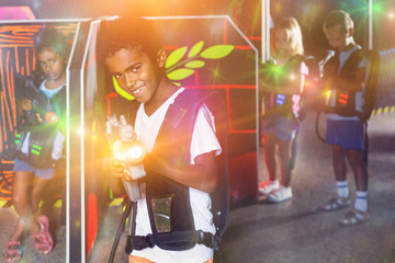 Obraz na płótnie Canvas Portrait of happy cheerful preteen boy with laser pistol posing in laser tag labyrinth