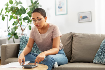 accounting, taxes and finances concept - young african american woman in glasses with papers and...
