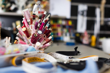 Workplace with spool of threads in sewing shop of variety clothes factory