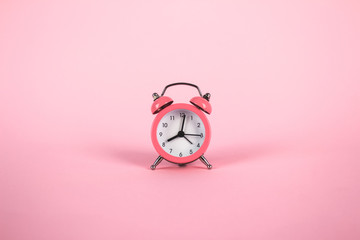 Pink alarm clock on pink background. Minimalistic flat lay image with copyspace and central composition. Time concept