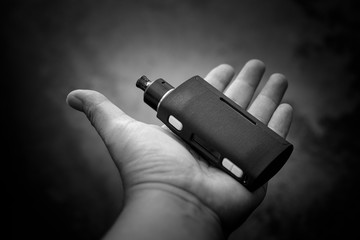 black and white, monochrome shot of high end regulated box mods with rebuildable dripping atomizer...
