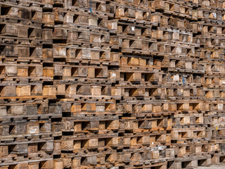 Stacked wooden pallets for industrial transportation. Piles of used pallets.
