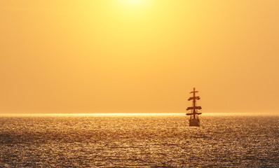 Seascape with sailing ship on sunset. Silhouette of sailing vessel floating in the sea. Copy space....