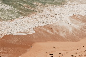 Pink sand beach with water wave ripple
