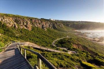 Fototapeta na wymiar Wooden walkway going down to the sea. There are cliffs in the background