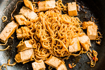 Frying yellow noodles with tofu in pan , Asian food