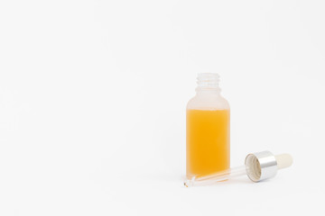 Collagen moisturizing hyaluron serum with orange liquid in a light matt bottle with pipette isolated on grey background.
