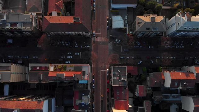 Drone aerial view of Milan skyline from above with colourful sunset over the city. Shot in Lambrate area during Coronavirus lockdown quarantine. Moving forward facing down at the streets.