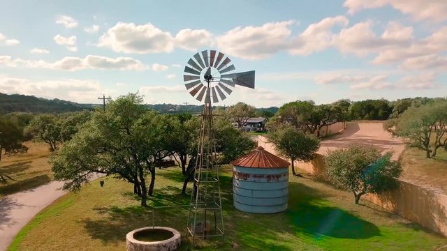 Drone shot of Farmland&rsquo;s old rusty windmill and Water well on a blue sky summer day