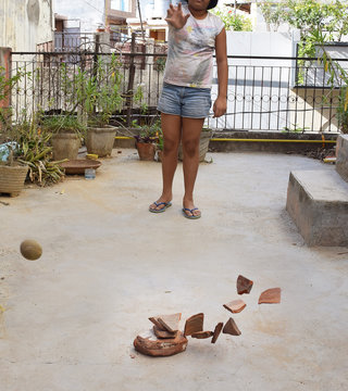 A perfect hit by an Indian girl playing an Old Village Game called as Pitthoo in Hindi Language. Here a ball is aimed at pieces of stones or marble to dislodge them