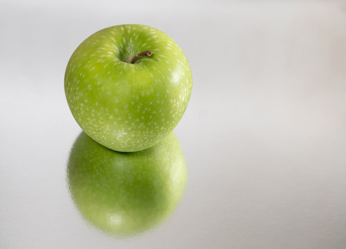 Bright green apple isolated and reflected, closeup