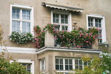 Fototapeta na wymiar Cozy balcony with pink flowers in an old building in Gdansk, Poland