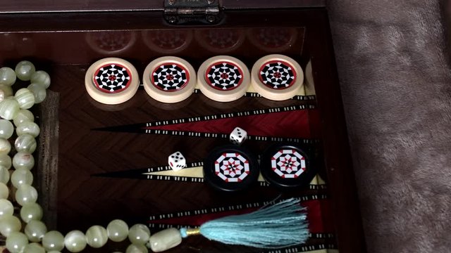A man plays backgammon and throws dice on the playing field and five and three fall out