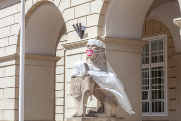 Stone old lion sculpture in white medical coat and mask in city center. Write on mask in Ukrainian "Thanks you doctors!" in Lviv, Ukraine