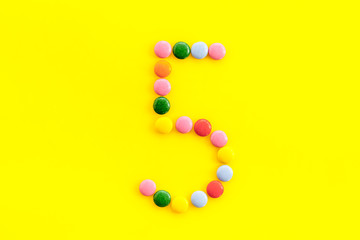 Candies font. Number 5 - five - on yellow background top view