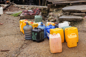 Cluster of plastic containers next to public source for drinking water at home in a floating wooden village in Port Moresby