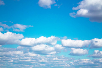 White fluffy clouds on a boundless blue sky. Nature background.