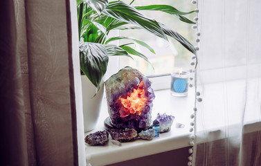 Using semi precious stone crystal details in home concept. Amethyst geode lamp burning, spiritual...