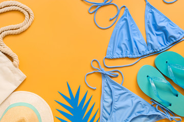 Set of beach accessories for relaxation. Swimsuit, hat, flip flops, bag on a yellow background. Summer vacation travel concept. Top view, flat lay.