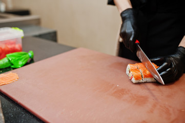 Close up hands of professional chef wear in black gloves making sushi and rolls in a restaurant kitchen of japanese traditional food.