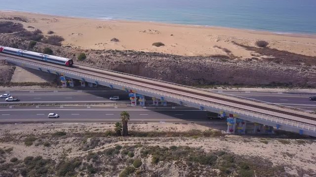 Passenger Train crossing a highway bridge with traffic passing below, Top down aerial view.