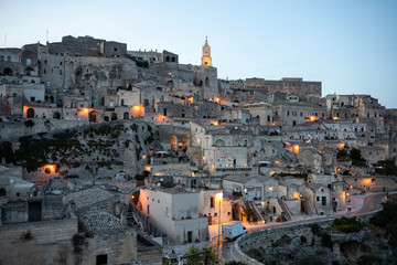 Fototapeta premium Evening view of the city of Matera; Italy; with the colorful lights highlighting old buildings in the Sassi di Matera a historic district in the city of Matera. Basilicata. Italy