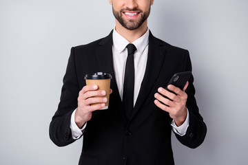 Cropped photo of positive agent man smm worker use his smartphone hold espresso hot caffeine beverage mug wear black blazer jacket isolated over grey color background