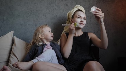 young mother and little daughter white mask with cucumbers on her face - Powered by Adobe