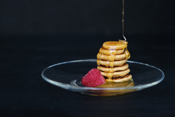 Tiny pancake cereal - trendy quarantine food. Pyramid of mini pancakes in plate with fresh...