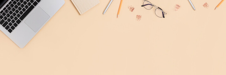 Top view of laptop, glasses and stationery on a beige background. Student workspace concept banner with place for text.