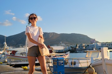 Naklejka premium Beautiful girl teenager walking along sea promenade, pier with yachts