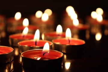 Close-Up Of Candles Burning On Table Against Black Background