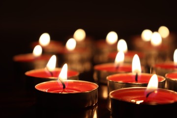 Close-Up Of Candles Burning On Table Against Black Background