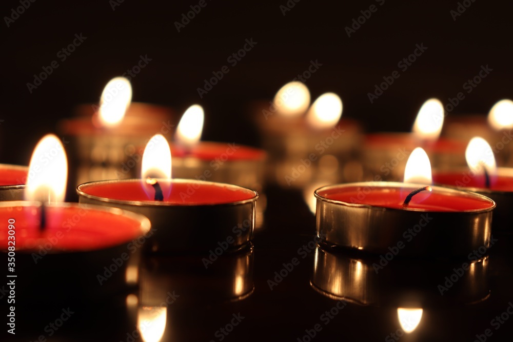 Wall mural close-up of candles burning on table against black background