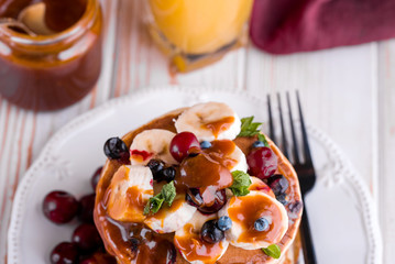 Delicious homemade pancakes with banana, berries, salted caramel, mint, tea.