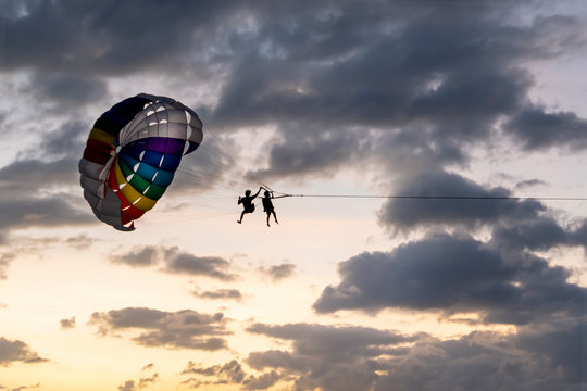 people ride, fly on a parachute along the coast over the sea against the background of a wonderful sunset. Attraction entertainment for tourists in the sea resorts of Thailand, Asia and around the