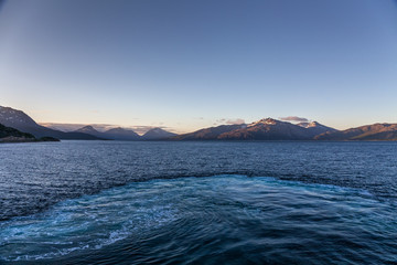A mystical fjord in Norway with mountains and fog hanging over the water in polar day. midnight...
