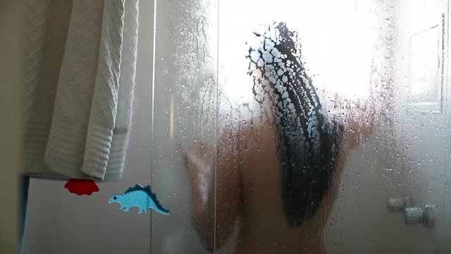 Woman taking shower, casual candid person showering and washing seen through window