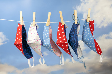 Colorful homemade community face masks for protection from coronavirus pandemic are hanging on a...